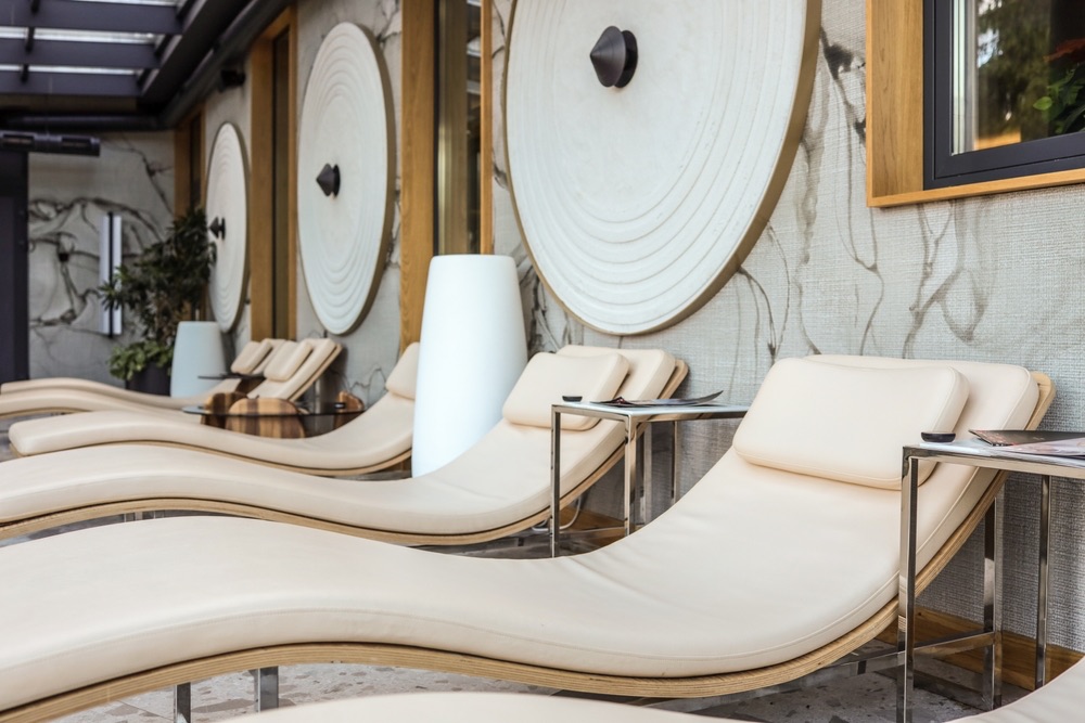 Cream reclining loungers in a modern spa relaxation area with warm wood accents.